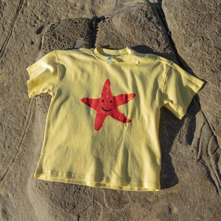 Starfish Tee Yellow - flat lay front view on rocks