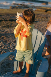 Green Reef Shorts - boy listening to shell with Starfish Tee Yellow
