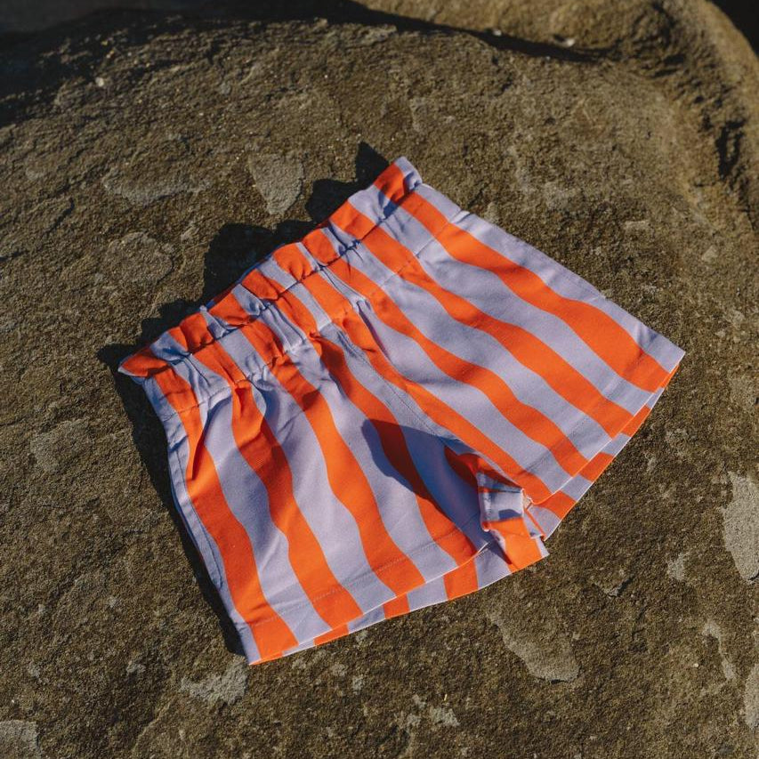 Pipi Shorts - flat lay on beach rocks front view