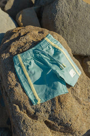 Green Reef Shorts - flat lay on beach rocks front view