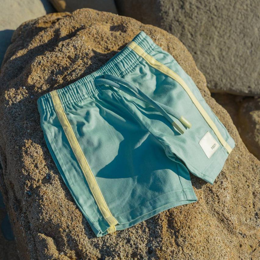 Green Reef Shorts - flat lay on beach rocks front view