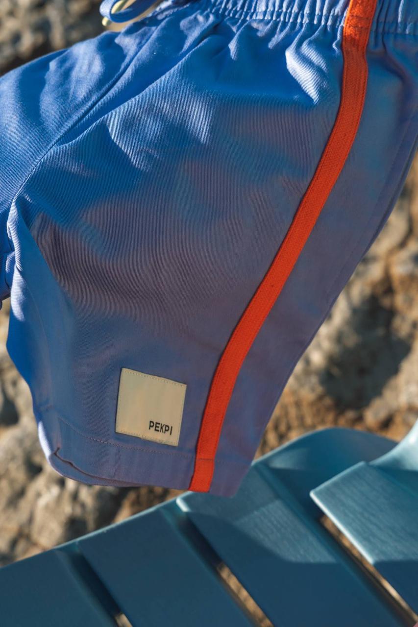 Blue Reef Shorts - Pekpi label and orange stripe close up