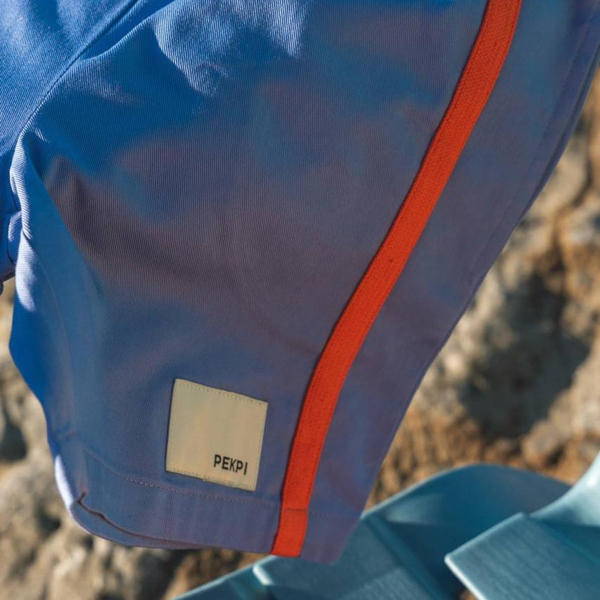 Blue Reef Shorts - Pekpi label and orange stripe close up