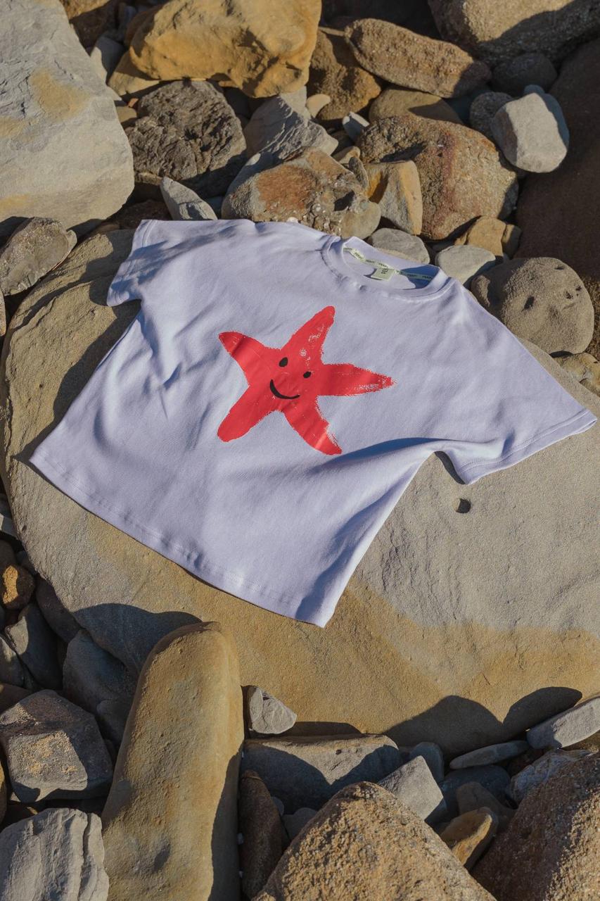 Starfish Tee Crop Purple - flat lay on beach rocks