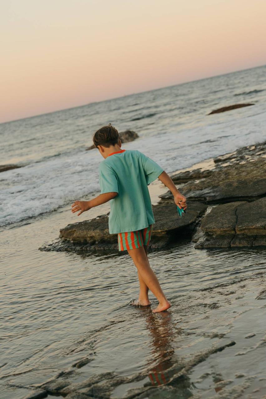 Sea Tee Green - boy playing in ocean sunset