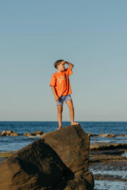 Blue Reef Shorts - boy standing on rock looking out to sea